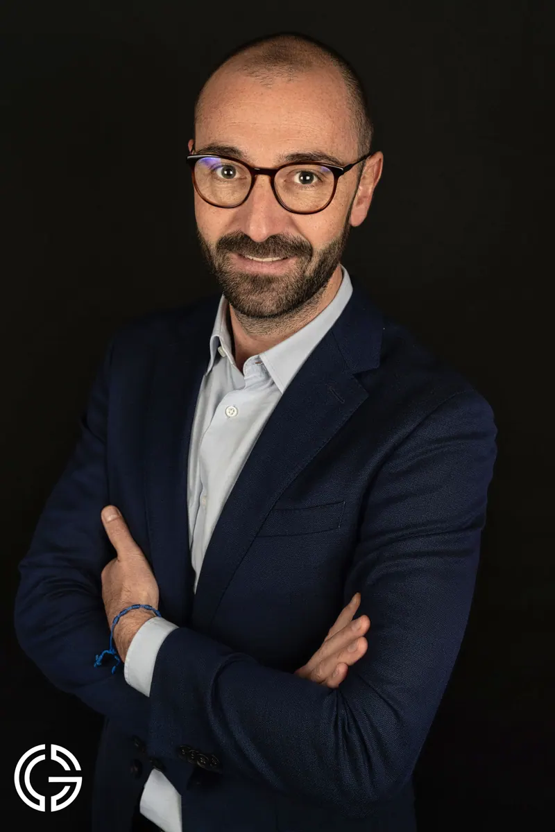 Portrait couleur d'un homme à lunettes en veste bleu marine.