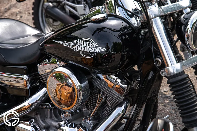 Gros plan sur le réservoir noir et chromé d'une Harley-Davidson.