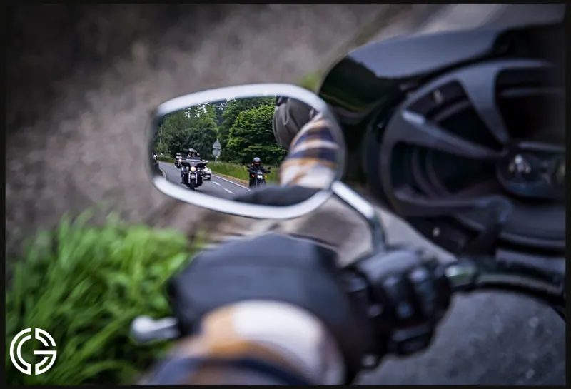 Une colonne de motos se reflète dans le rétroviseur d'une moto.