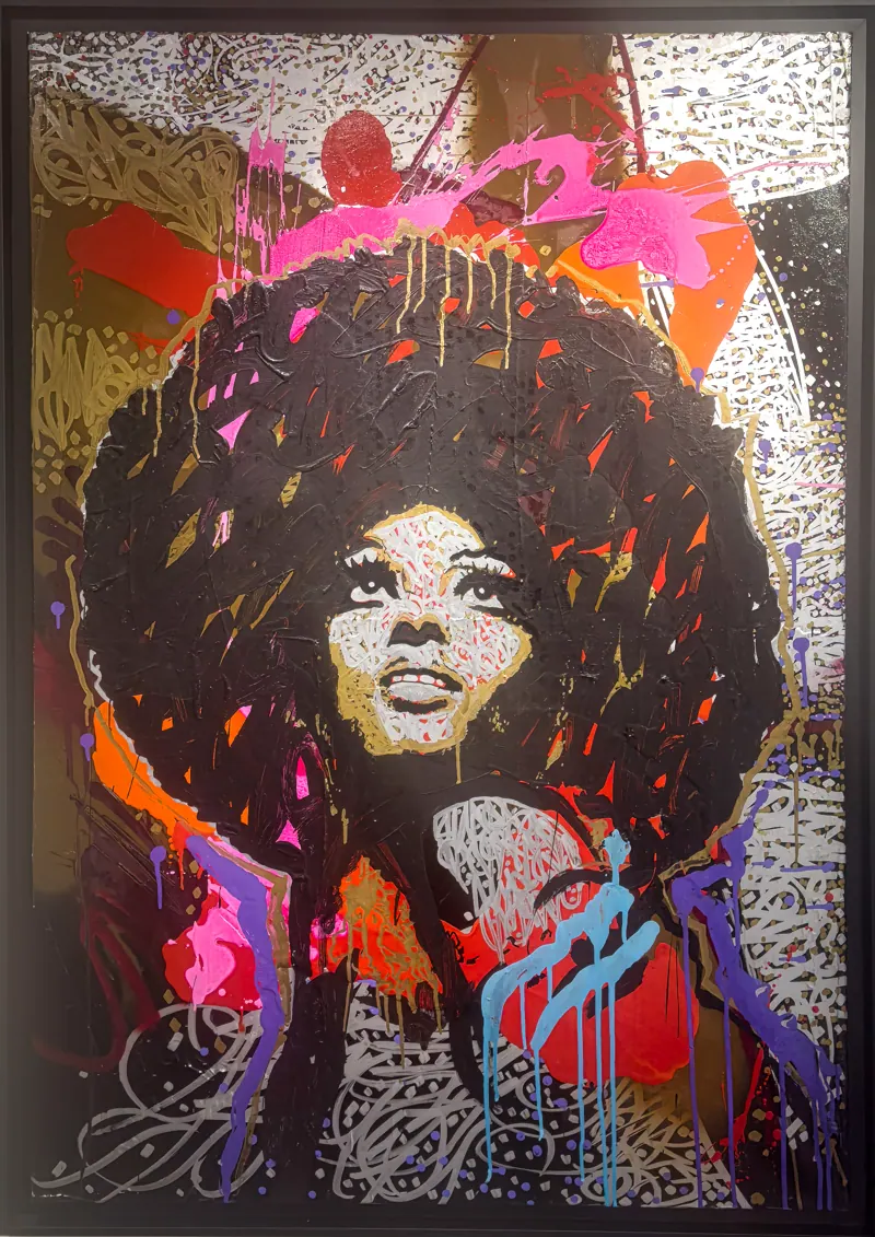 Visage de femme à la coiffure afro, éclaboussures de couleurs vives.