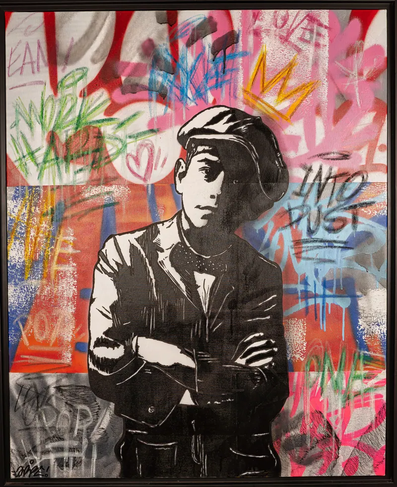 Jeune homme bras croisés devant des graffitis colorés.