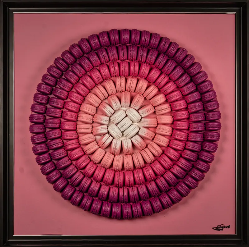 Cercle de macarons dans un dégradé de roses sur fond rose, encadré noir.